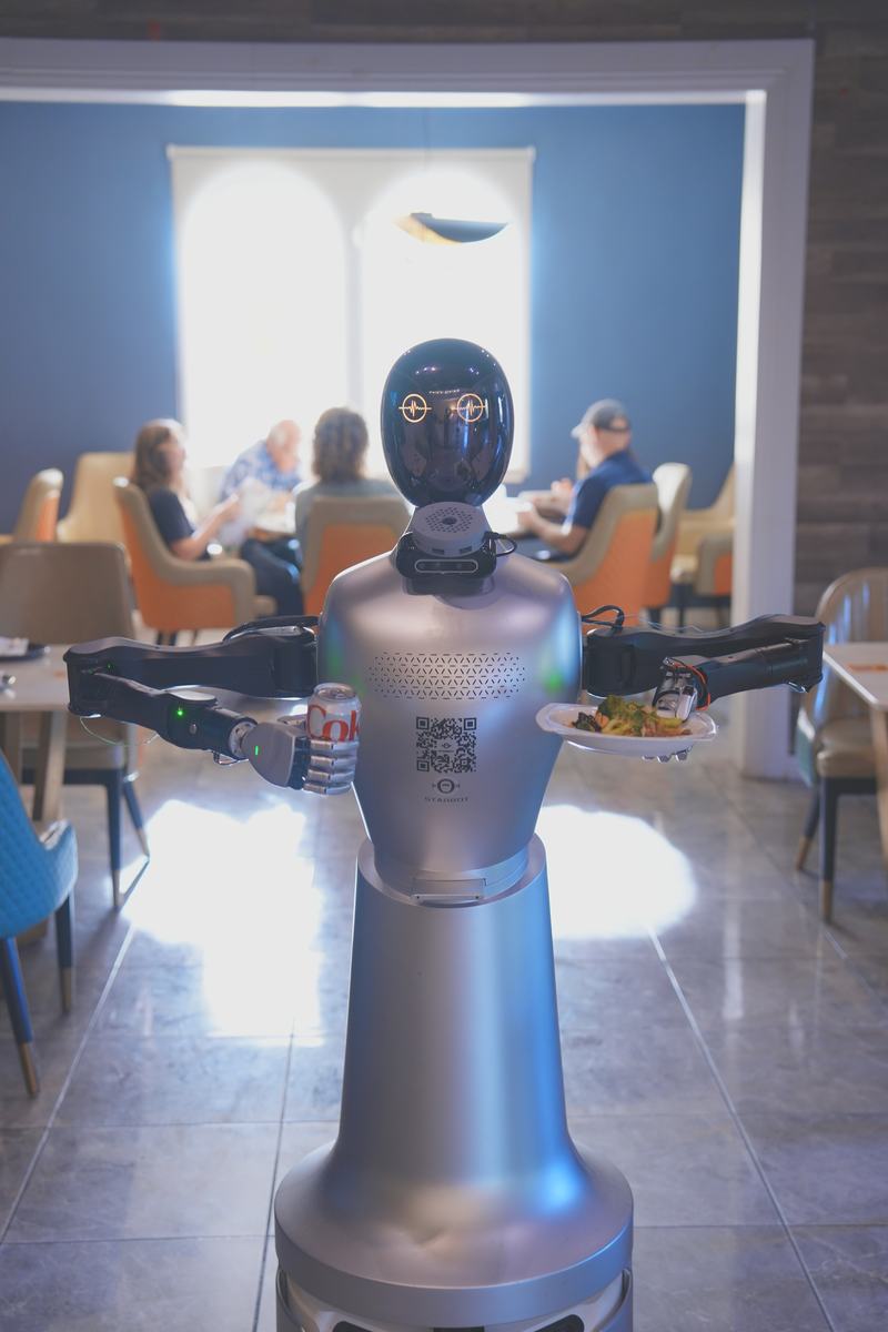 StarBot Nova carrying a drink and a plated dish across a full dining room