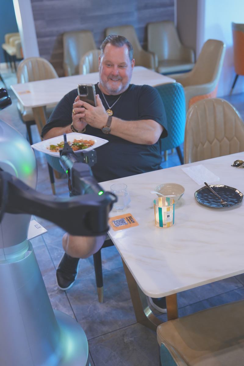 A guest photographing StarBot Nova as it serves the table